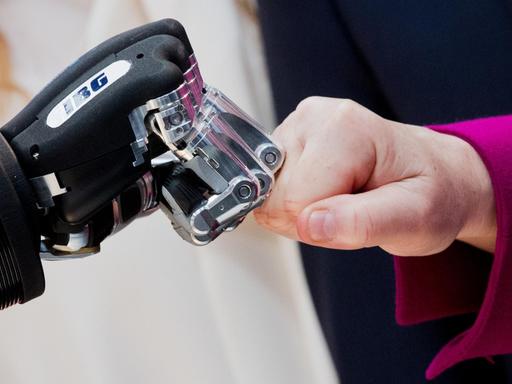 Eine Roboterhand bildet eine Faust und stößt gegen eine menschliche Faust
