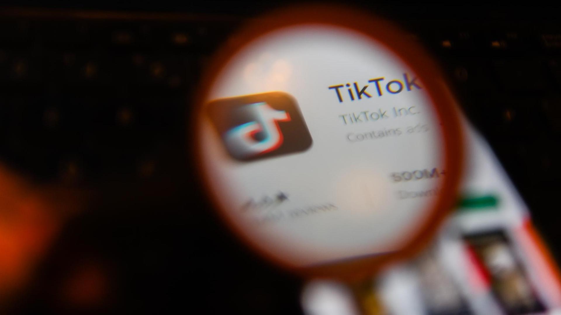 Die App Tik Tok auf einem Smartphonebildschirm durch eine Lupe gesehen. Die App Tik Tok auf einem Smartphonebildschirm durch eine Lupe gesehen.