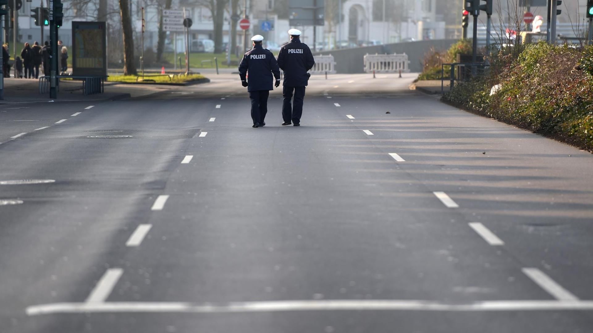 Polizisten gehen in Düsseldorf über eine gesperrte Strasse. Polizisten gehen in Düsseldorf über eine gesperrte Strasse.
