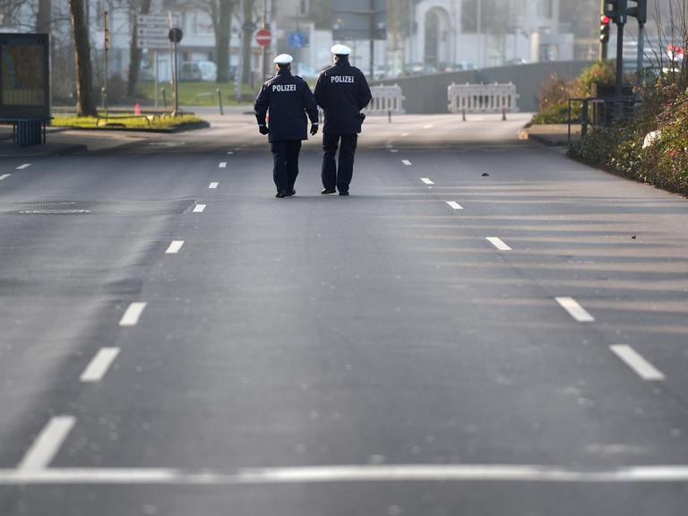 Polizisten gehen in Düsseldorf über eine gesperrte Strasse.