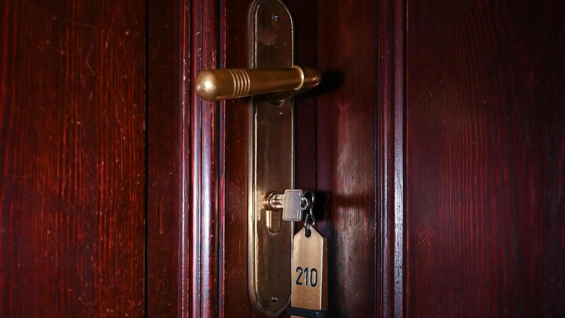 Ein Schlüssel steckt im Schloss zu einem Hotelzimmer Ein Schlüssel steckt im Schloss zu einem Hotelzimmer