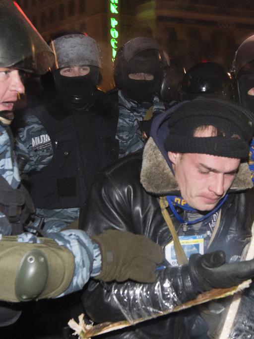 Polizisten mit einem Demonstrenten am 11. Dezember 2013 in Kiew