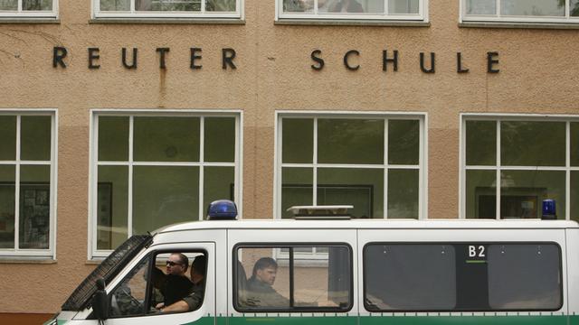 Polizisten laufen an Polizei-Einsatzfahrzeugen vorbei, die vor der Ernst-Reuter Schule in Berlin geparkt sind. Das Foto ist vom Mai 2007. Damals kam es zu einem Zwischenfall, bei dem ein 21-Jähriger und ein 16-Jähriger durch ein Messer verletzt wurden.