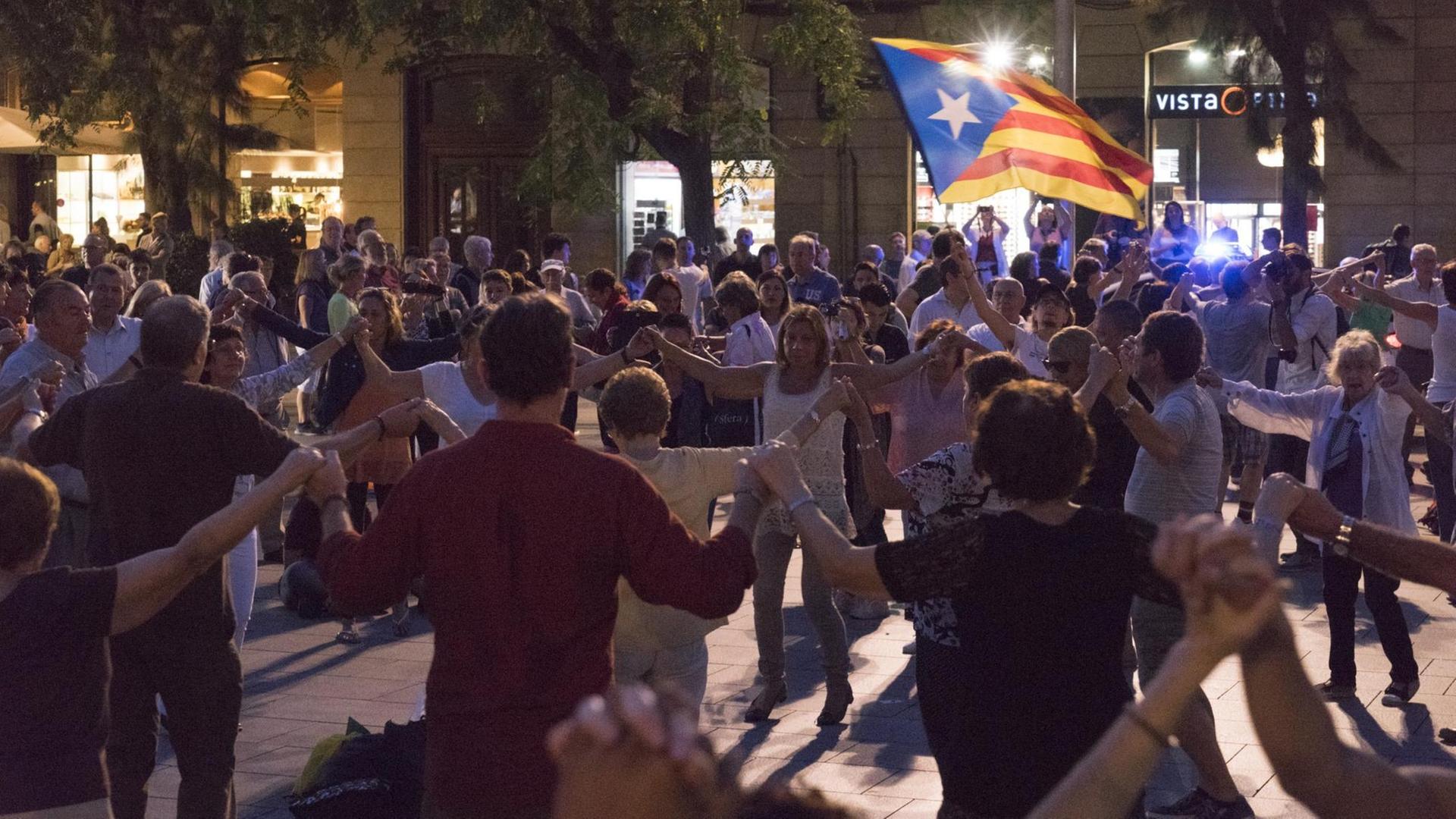 Katalanen tanzen Sardana in Barcelona mit der Fahne der katalanischen Unabhängigkeitsbewegung Katalanen tanzen Sardana in Barcelona mit der Fahne der katalanischen Unabhängigkeitsbewegung