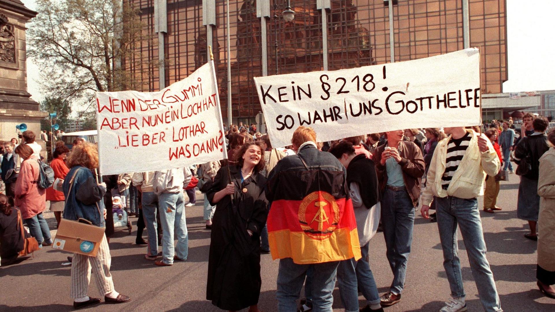 Protest am 22. April 1990 gegen eine Übernahme des bundesdeutschen Abtreibungsgesetzes Paragraph 218 vor der Volkskammer in Ost-Berlin. Mehrere Personen halten Transparente hoch.