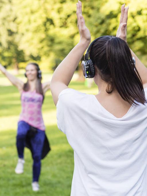 Beim schweißtreibenden "Silent Zumba" in einem Münchner Park trainieren die Teilnehmerinnen zur Musik aus Kopfhörern, wodurch Lärmkonflikte mit Spaziergängern und anderen Ruhesuchenden vermieden werden sollen.