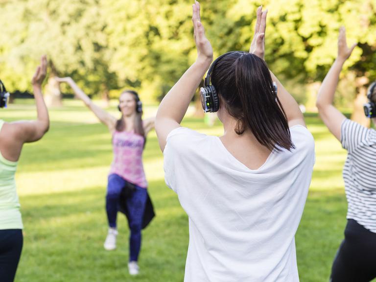 Beim schweißtreibenden "Silent Zumba" in einem Münchner Park trainieren die Teilnehmerinnen zur Musik aus Kopfhörern, wodurch Lärmkonflikte mit Spaziergängern und anderen Ruhesuchenden vermieden werden sollen.