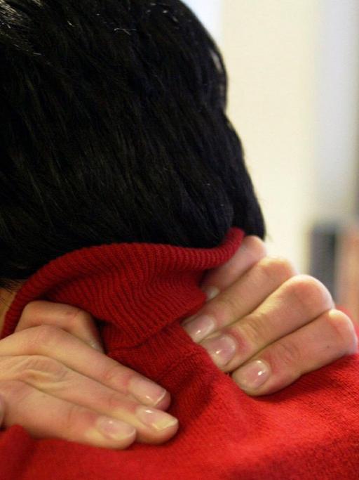 Ein junge Frau mit Verspannungen und Schmerzen im Halswirbelbereich.