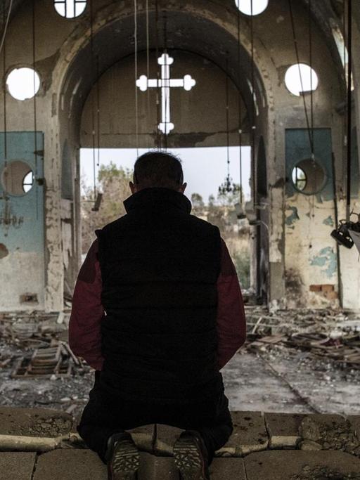 Ein Bewohner der Provinz Al-Hasake in Syrien betet in einer Kirche, die vom Islamischen Staat zerstört wurde.