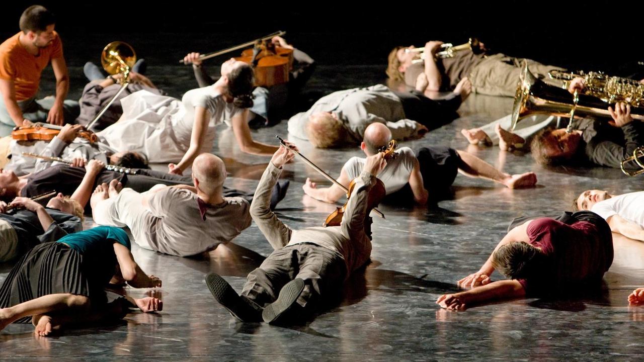ARCHIV - Mitglieder des Ensemble Modern liegen während der Uraufführung von Wolfgang Rihms "Jagden und Formen (Zustand 2008)" auf der Bühne. ARCHIV - Mitglieder des Ensemble Modern liegen während der Uraufführung von Wolfgang Rihms "Jagden und Formen (Zustand 2008)" auf der Bühne.