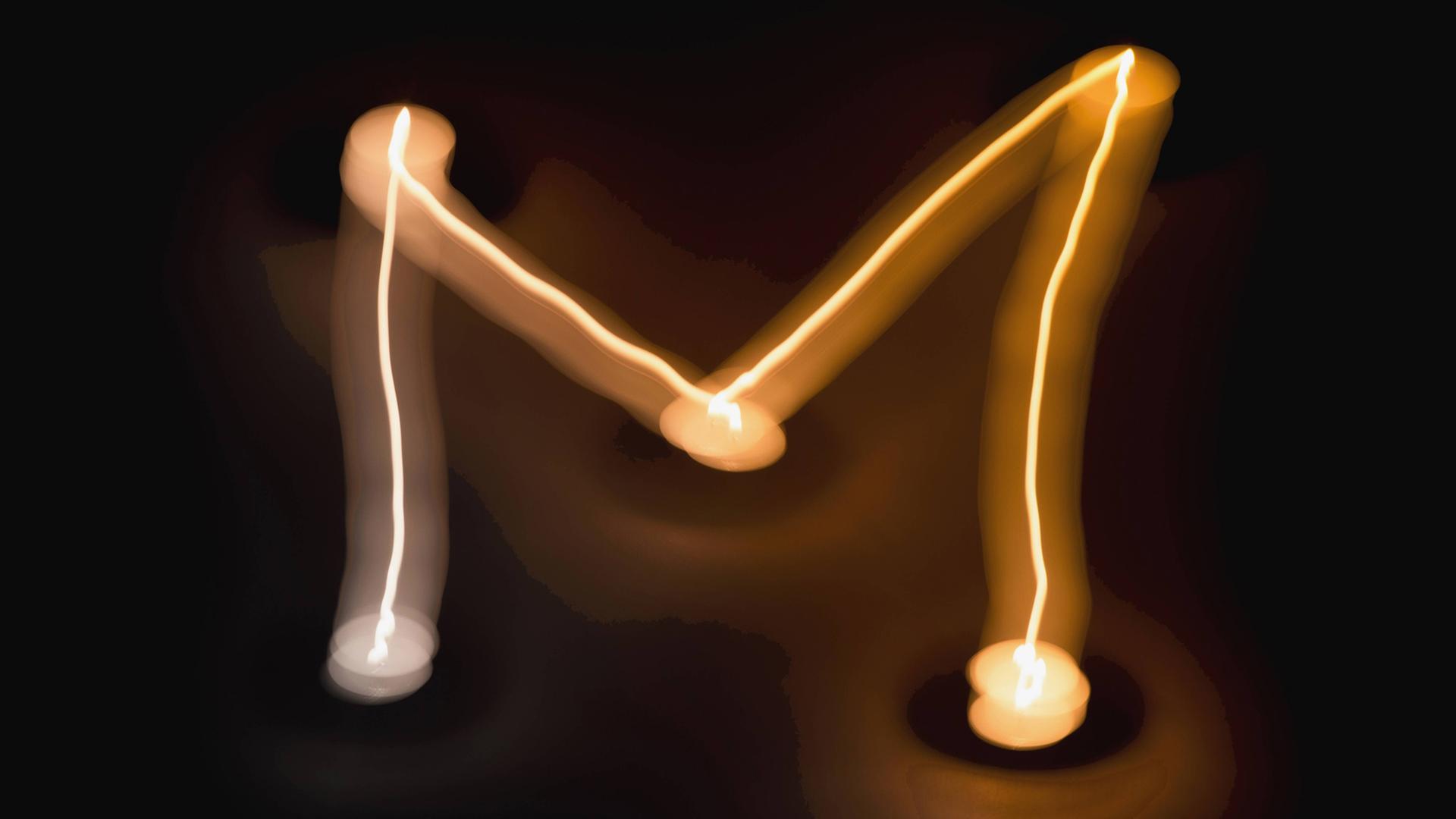Lichtspiel mit Kerzen, das den Buchstaben "M" formt Lichtspiel mit Kerzen, das den Buchstaben "M" formt