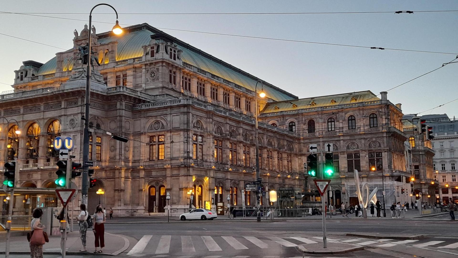 Die Wiender Staatsoper von außen fotografiert. Zu sehen sind ausserdem eine Kreutzung und einige Fußgänger*innen. Die Wiender Staatsoper von außen fotografiert. Zu sehen sind ausserdem eine Kreutzung und einige Fußgänger*innen.