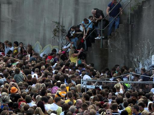 Menschen stehen dichtgedrängt vor und auf einer Treppe an einem Tunnelausgang in Duisburg.