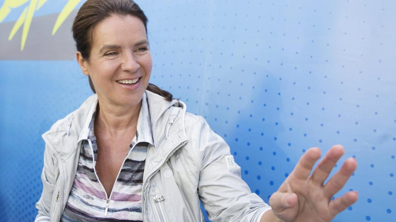 Porträt von Katarina Witt vor einer Fotowand bei einem Firmenlauf Porträt von Katarina Witt vor einer Fotowand bei einem Firmenlauf