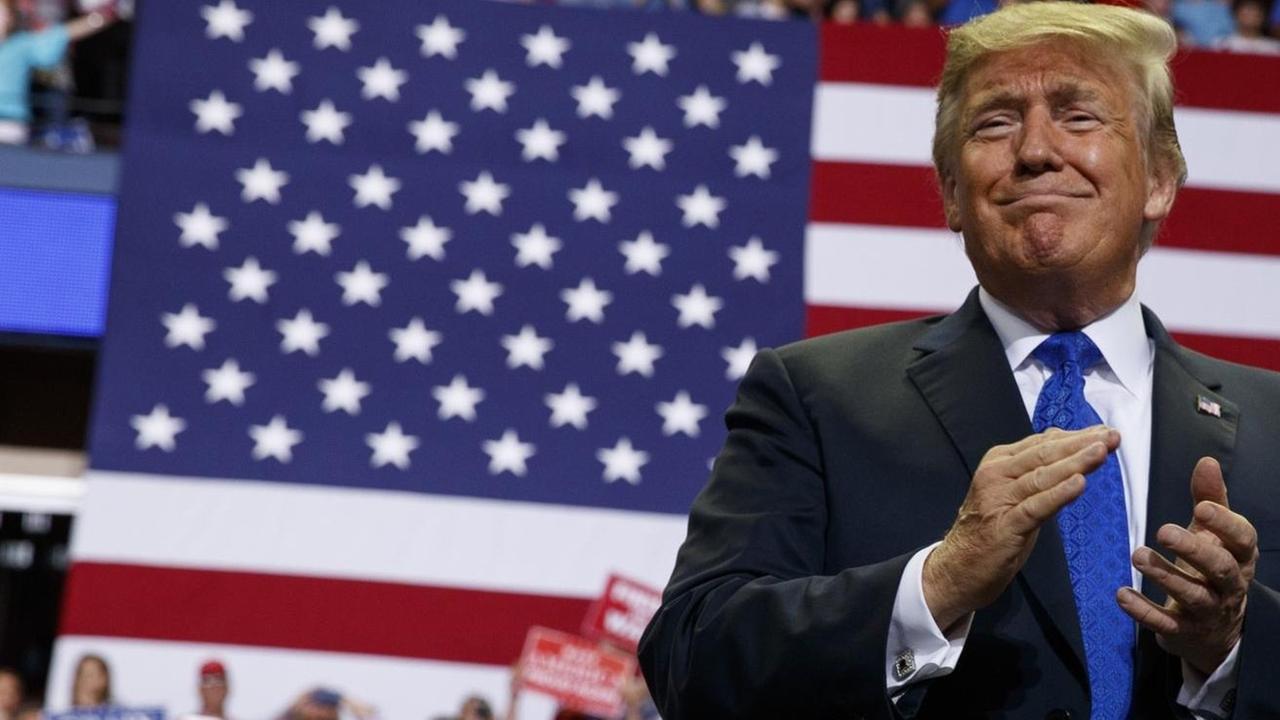 USA, Southaven: Donald Trump, Präsident der USA, spricht auf einer Kundgebung in der Landers Center Arena. Er klatscht in die Hände und verzieht das Gesicht zu einer Grimasse. Im Hintergrund sitzen Anhänger.