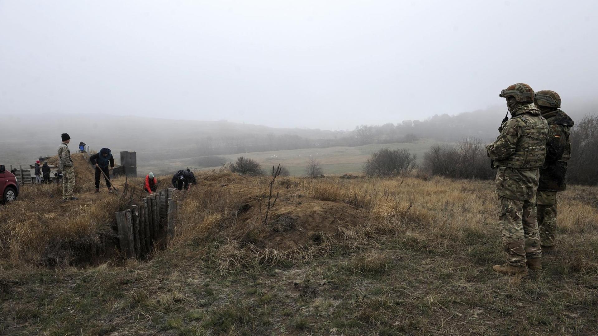 Ukrainische Sicherheitskräfte beobachten Aktivisten, die Gräben nahe des Asowschen Meers graben. Ukrainische Sicherheitskräfte beobachten Aktivisten, die Gräben nahe des Asowschen Meers graben.