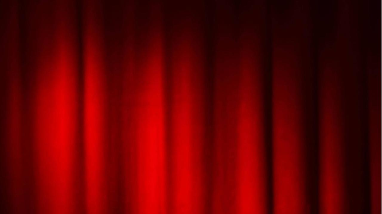 Ein Spot ist auf einen roten Bühnenvorhang gerichtet.
