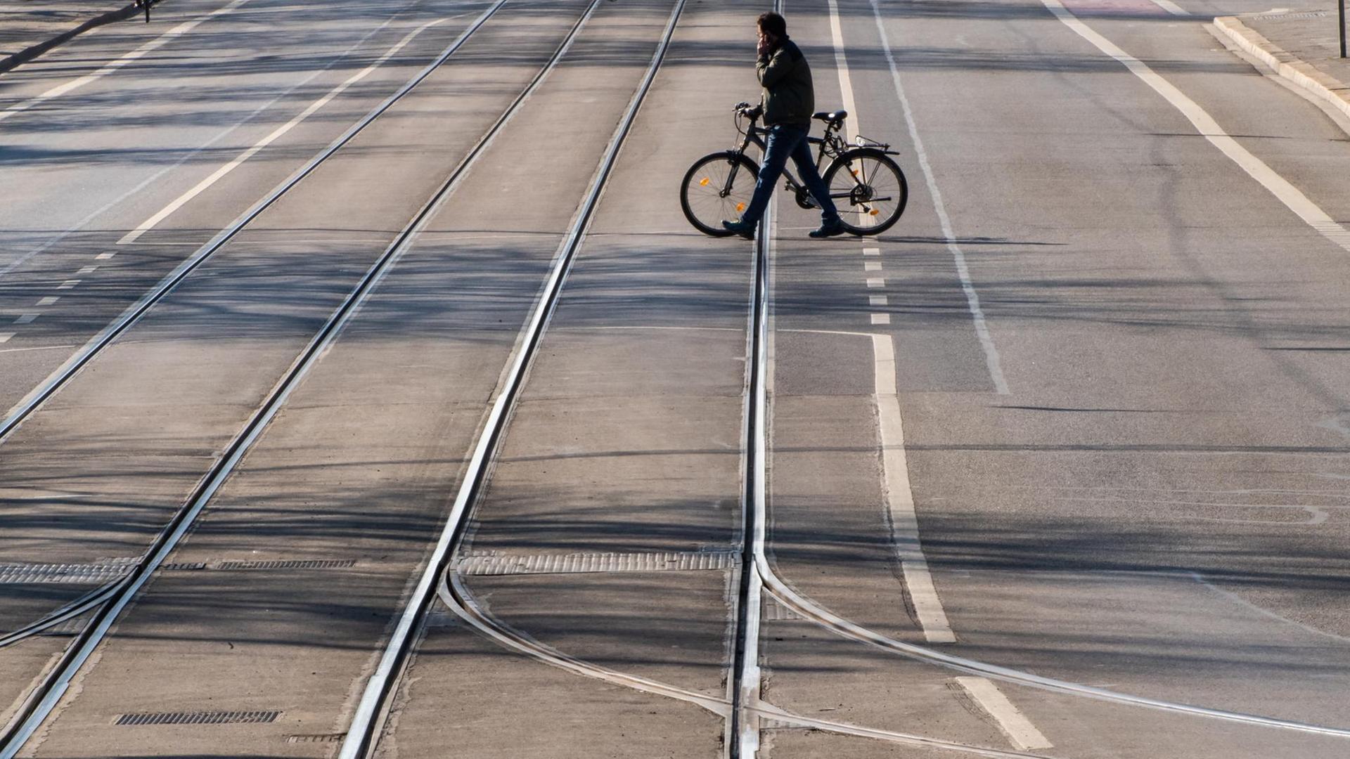 Ein Mann überquert mit einem Fahrrad eine leere Straße Ein Mann überquert mit einem Fahrrad eine leere Straße
