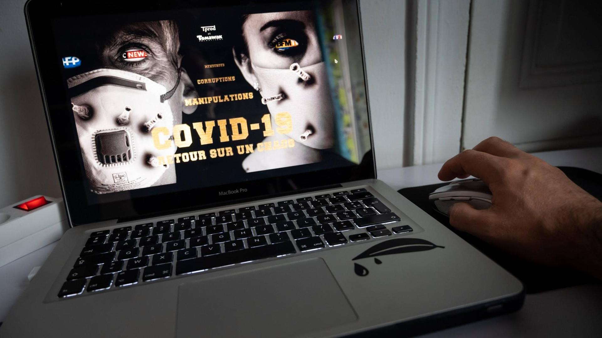 Ein Laptop hat den Streaming-Film "Hold Up" des früheren französischen Journalisten Pierre Barnérias geladen, der angeblich die Wahrheit über Covid-19 erzählt. Auf dem Bildschirm sieht man recht und links je ein Gesicht mit Maske und in der Mitte steht "Covid-19 - Retour sur un chaos" (Blick auf ein Chaos). Ein Laptop hat den Streaming-Film "Hold Up" des früheren französischen Journalisten Pierre Barnérias geladen, der angeblich die Wahrheit über Covid-19 erzählt. Auf dem Bildschirm sieht man recht und links je ein Gesicht mit Maske und in der Mitte steht "Covid-19 - Retour sur un chaos" (Blick auf ein Chaos).
