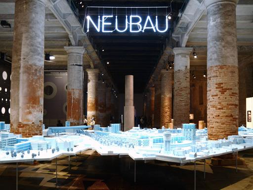 Die 15. Biennale der Architektur in Venedig läuft vom 28.05. bis 27.11.2016. Zu sehen ist eine Achitekturinstallation, darüber hängt der Schriftzug "Neubau" als Neonröhre