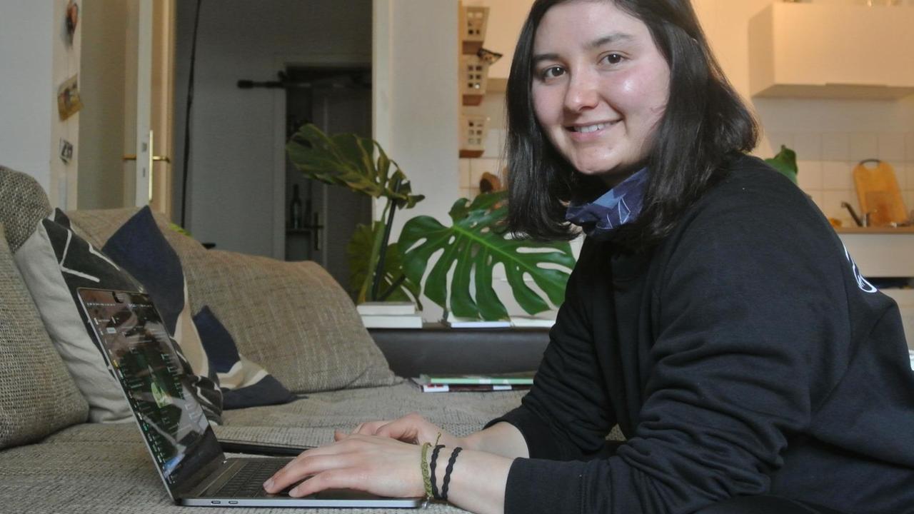 Eine junge Frau sitzt in einem Zimmer vor einem Computer. Eine junge Frau sitzt in einem Zimmer vor einem Computer.