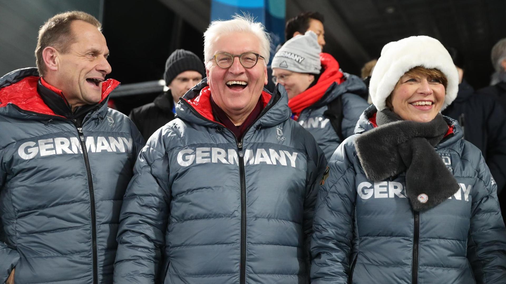 Bundespräsident Frank-Walter Steinmeier lacht mit seiner Frau Elke Büdenbender und Alfons Hörmann, DOSB-Präsident des Deutschen Olympischen Sportbundes, bei der Siegerehrung für Biathletin Dahlmeier.
