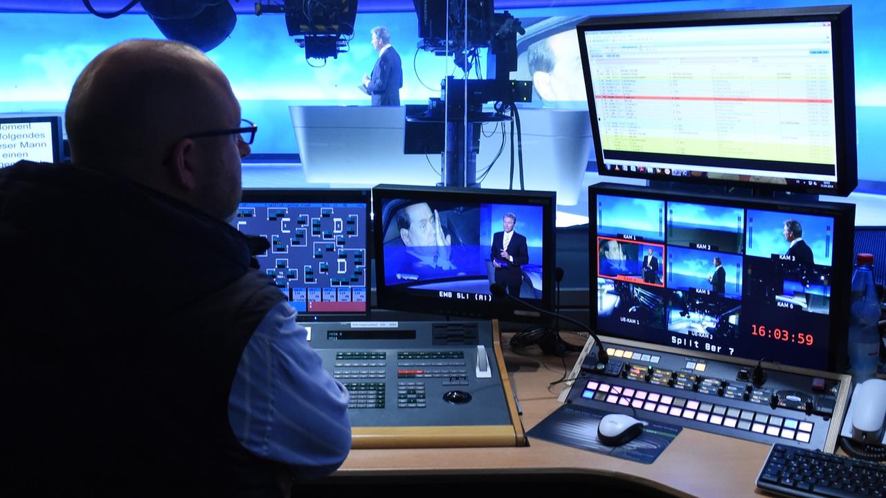 Ein Redakteur sitzt im Regieraum der ARD-Tagesschau vor eine Reihe Fernseh- und Computermonitoren. Ein Redakteur sitzt im Regieraum der ARD-Tagesschau vor eine Reihe Fernseh- und Computermonitoren.