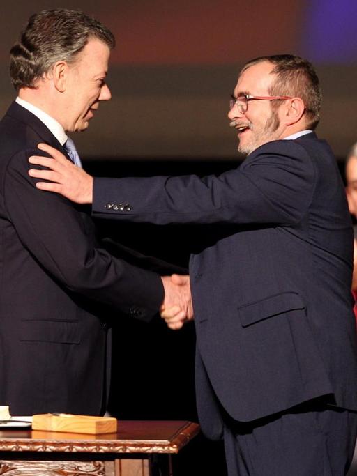 Kolumbianischer Präsident Juan Manuel Santos und FARC-Kommandeur Rodrigo Londoño reichen sich die Hand.