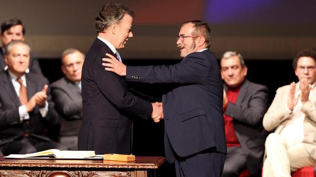 Kolumbianischer Präsident Juan Manuel Santos und FARC-Kommandeur Rodrigo Londoño reichen sich die Hand.