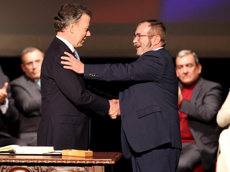 Kolumbianischer Präsident Juan Manuel Santos und FARC-Kommandeur Rodrigo Londoño reichen sich die Hand.