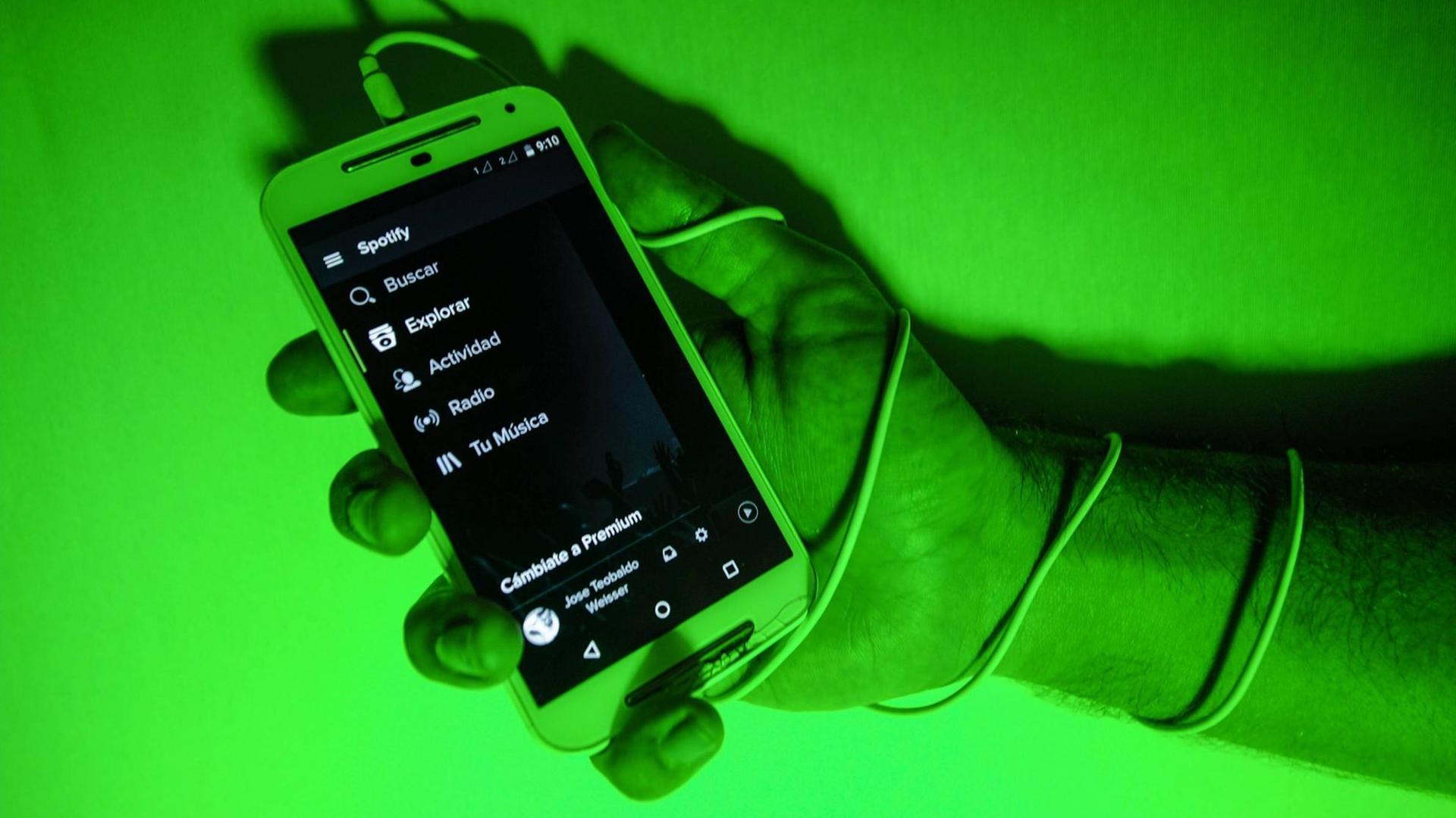 Hand hält Mobiltelefon, die Szene ist in grünes Licht getaucht. Hand hält Mobiltelefon, die Szene ist in grünes Licht getaucht.