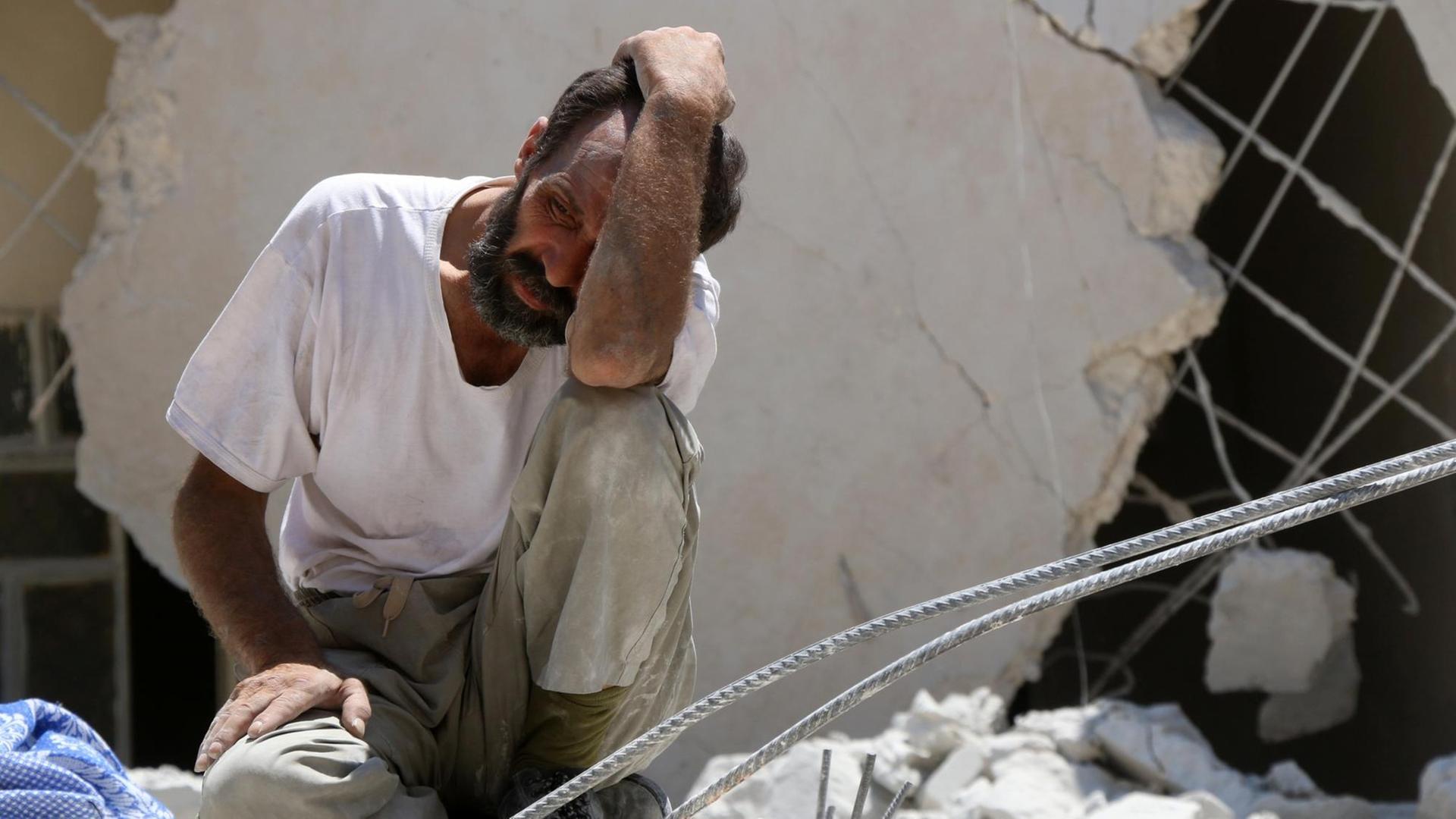 Ein Mann hält sich die Hand vor das Gesicht, er sitzt auf Trümmern. Das Foto entstand nach einem Bombenangriff in den Rebellenvierteln von Aleppo. Ein Mann hält sich die Hand vor das Gesicht, er sitzt auf Trümmern. Das Foto entstand nach einem Bombenangriff in den Rebellenvierteln von Aleppo.