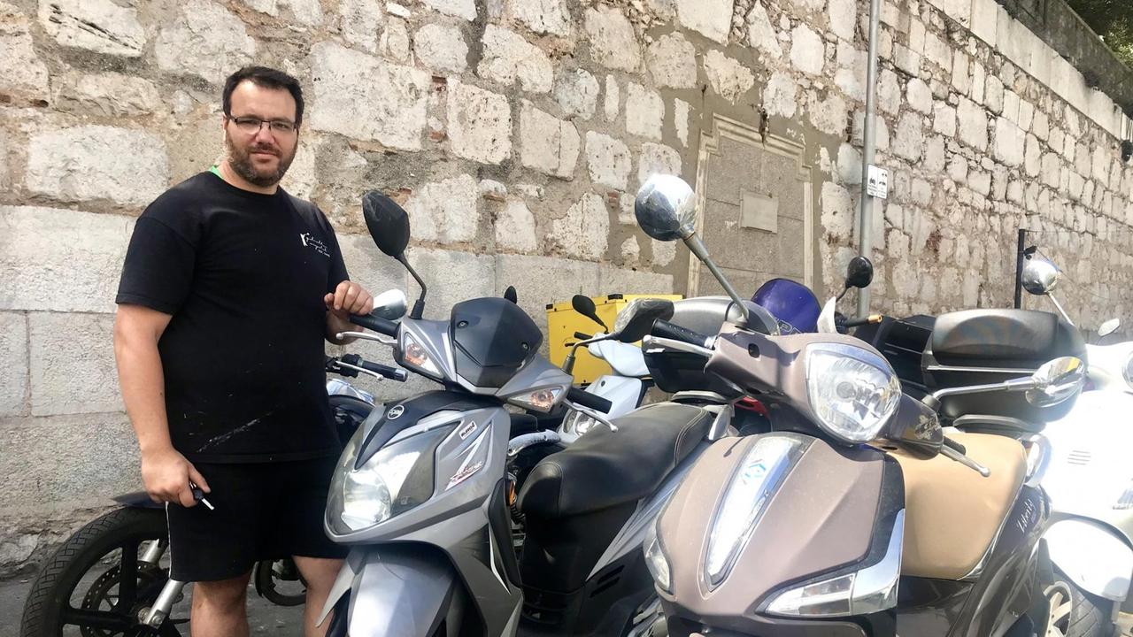 Juan steht vor seinem Motorroller. Juan steht vor seinem Motorroller.