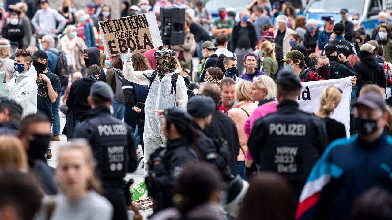 Ein Mann hält während einer Demo ein Schild mit der Aufschrift "Meditieren gegen Ebola" Ein Mann hält während einer Demo ein Schild mit der Aufschrift "Meditieren gegen Ebola"