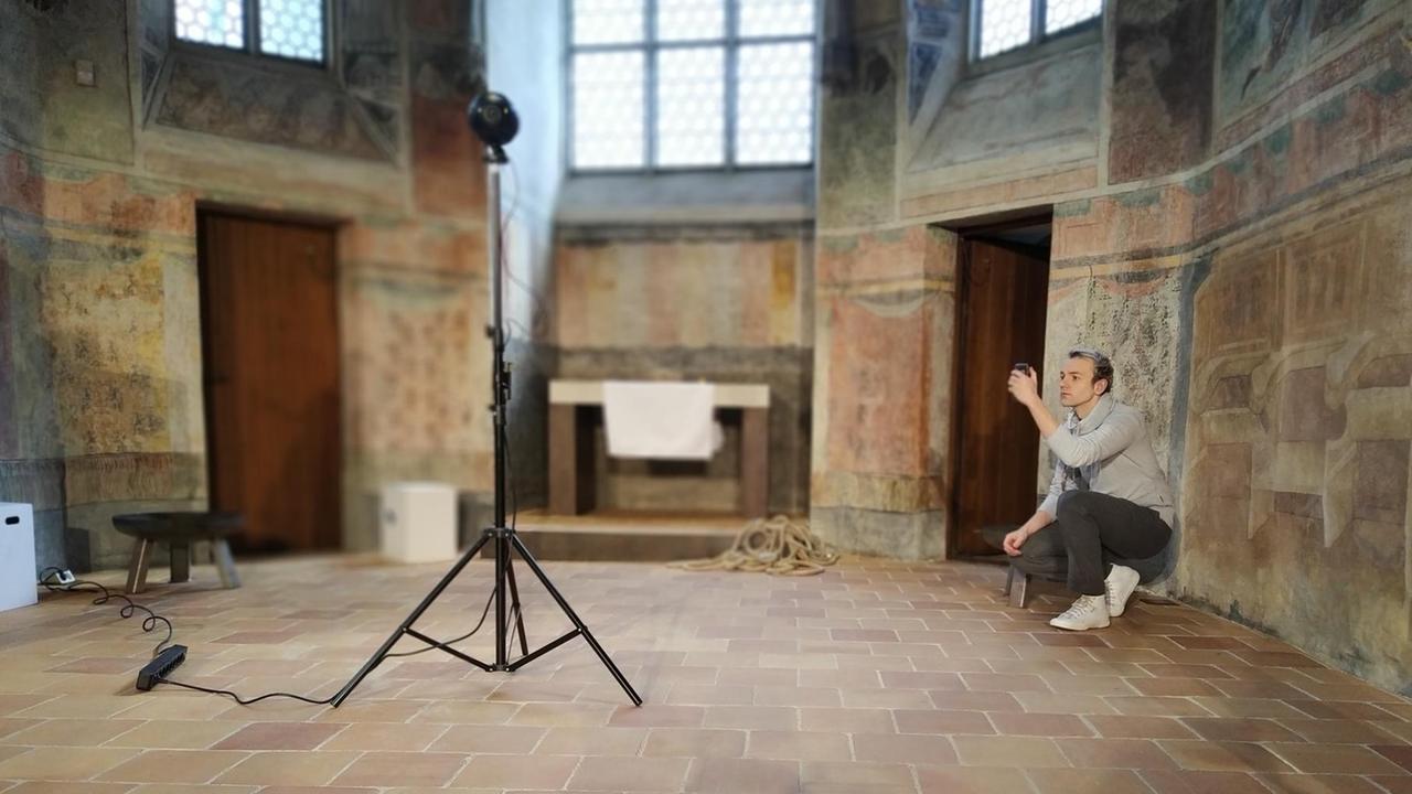 Ein Mann kniet in einer Kirche vor einer Kamera. Ein Mann kniet in einer Kirche vor einer Kamera.