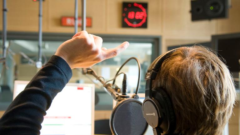 Radiofeuilleton - Studioszene mit Handzeichen Radiofeuilleton - Studioszene mit Handzeichen