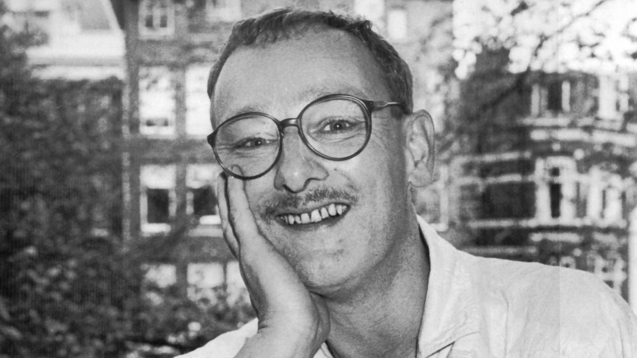 Das Gesicht in die Hand gestützt und mit großer runder Brille lacht der junge Konrad Boehmer in die Kamera Das Gesicht in die Hand gestützt und mit großer runder Brille lacht der junge Konrad Boehmer in die Kamera