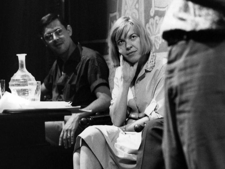 Auf dem schwarz-weiß Foto sitzt Ingeborg Bachmann mit übereinander geschlagenen Beinen und lauscht mit dem Kopf auf die rechte Hand gestützt der Kamera zugewandt einem Vortrag beim Spoleto Literaturfestival 1965.