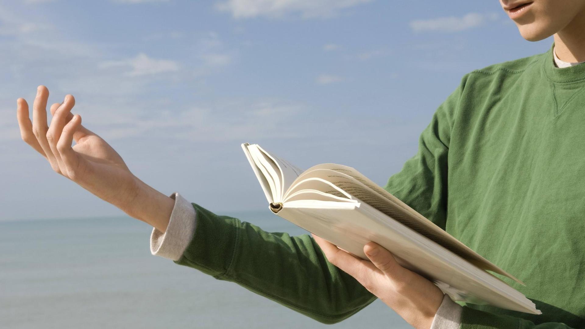 Ein junger Mann, am Strand, trägt ein Gedicht vor. Ein junger Mann, am Strand, trägt ein Gedicht vor.