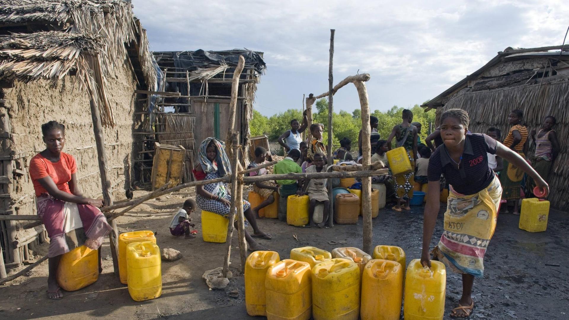 Frauen füllen an einer öffentlichen Trinkwasserversorgung in Quelimane, Mosambik, ihre Wasserkanister wieder auf