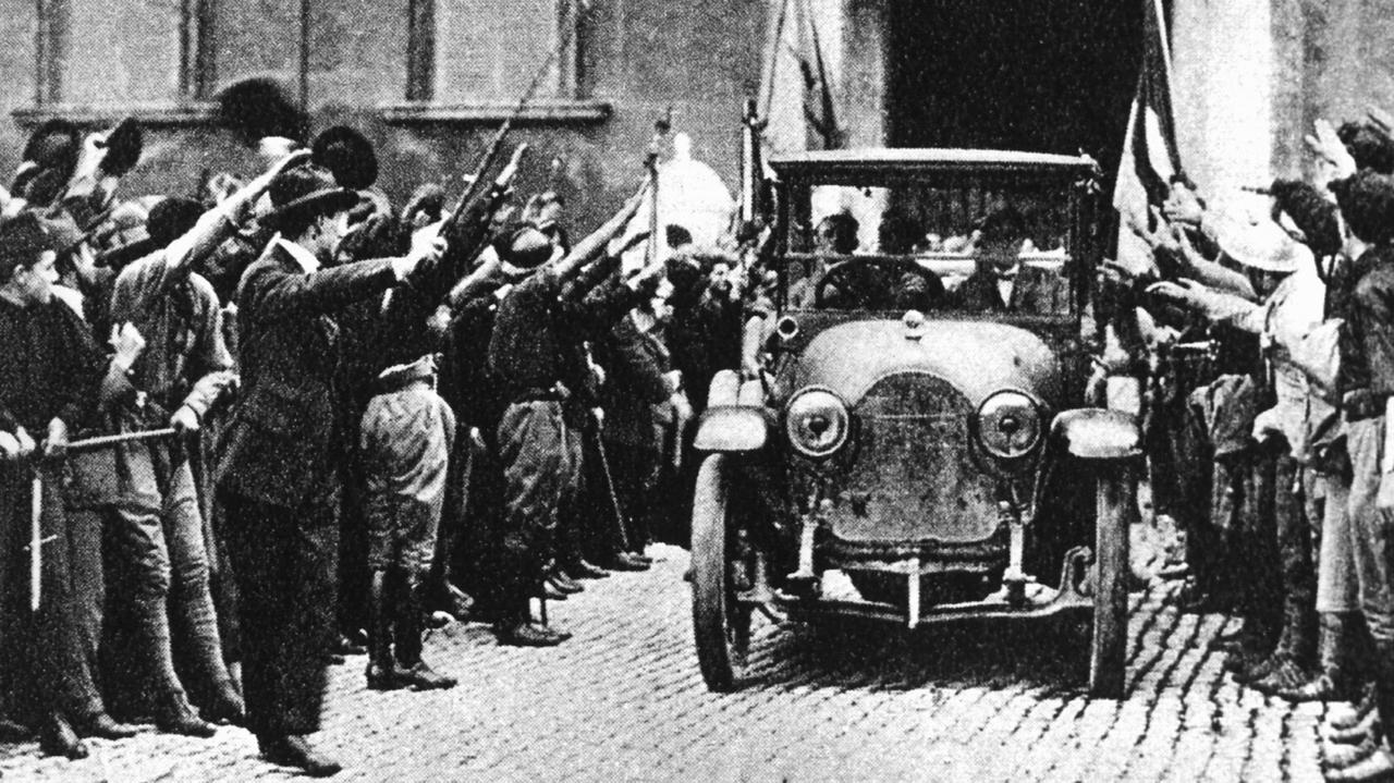 Historische schwarz-weiß-Aufnahme von 1922: Ein Auto fährt durch eine ihm zujubelnde Menschenmenge.