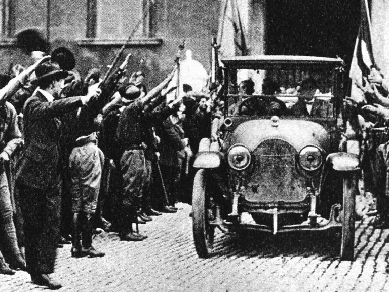 Historische schwarz-weiß-Aufnahme von 1922: Ein Auto fährt durch eine ihm zujubelnde Menschenmenge.