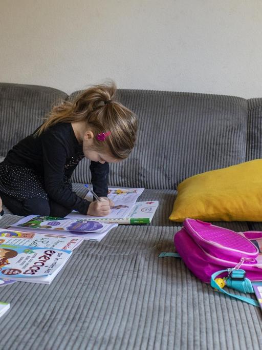 Abby, 6, mit ihrer Mutter Lisa beim Homeschooling auf dem Sofa zu Hause. Die Kuscheltiere sitzen auch alle vor einem Arbeitsheft. 20. März 2020 in Claira, Frankreich.