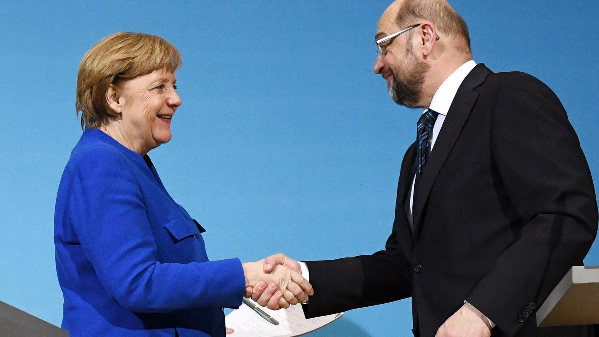 Der SPD-Parteivorsitzende Martin Schulz (r) und Bundeskanzlerin Angela Merkel (CDU) geben sich am 12.01.2018 im Willy-Brandt-Haus in Berlin nach einer Pressekonferenz die Hand. Der SPD-Parteivorsitzende Martin Schulz (r) und Bundeskanzlerin Angela Merkel (CDU) geben sich am 12.01.2018 im Willy-Brandt-Haus in Berlin nach einer Pressekonferenz die Hand.