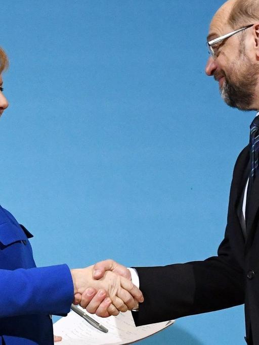 Der SPD-Parteivorsitzende Martin Schulz (r) und Bundeskanzlerin Angela Merkel (CDU) geben sich am 12.01.2018 im Willy-Brandt-Haus in Berlin nach einer Pressekonferenz die Hand.