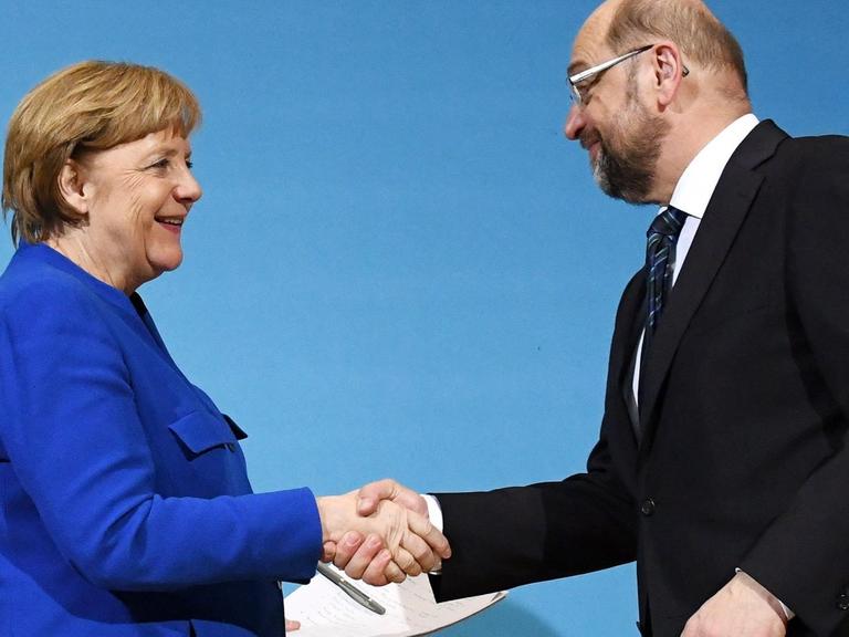 Der SPD-Parteivorsitzende Martin Schulz (r) und Bundeskanzlerin Angela Merkel (CDU) geben sich am 12.01.2018 im Willy-Brandt-Haus in Berlin nach einer Pressekonferenz die Hand.