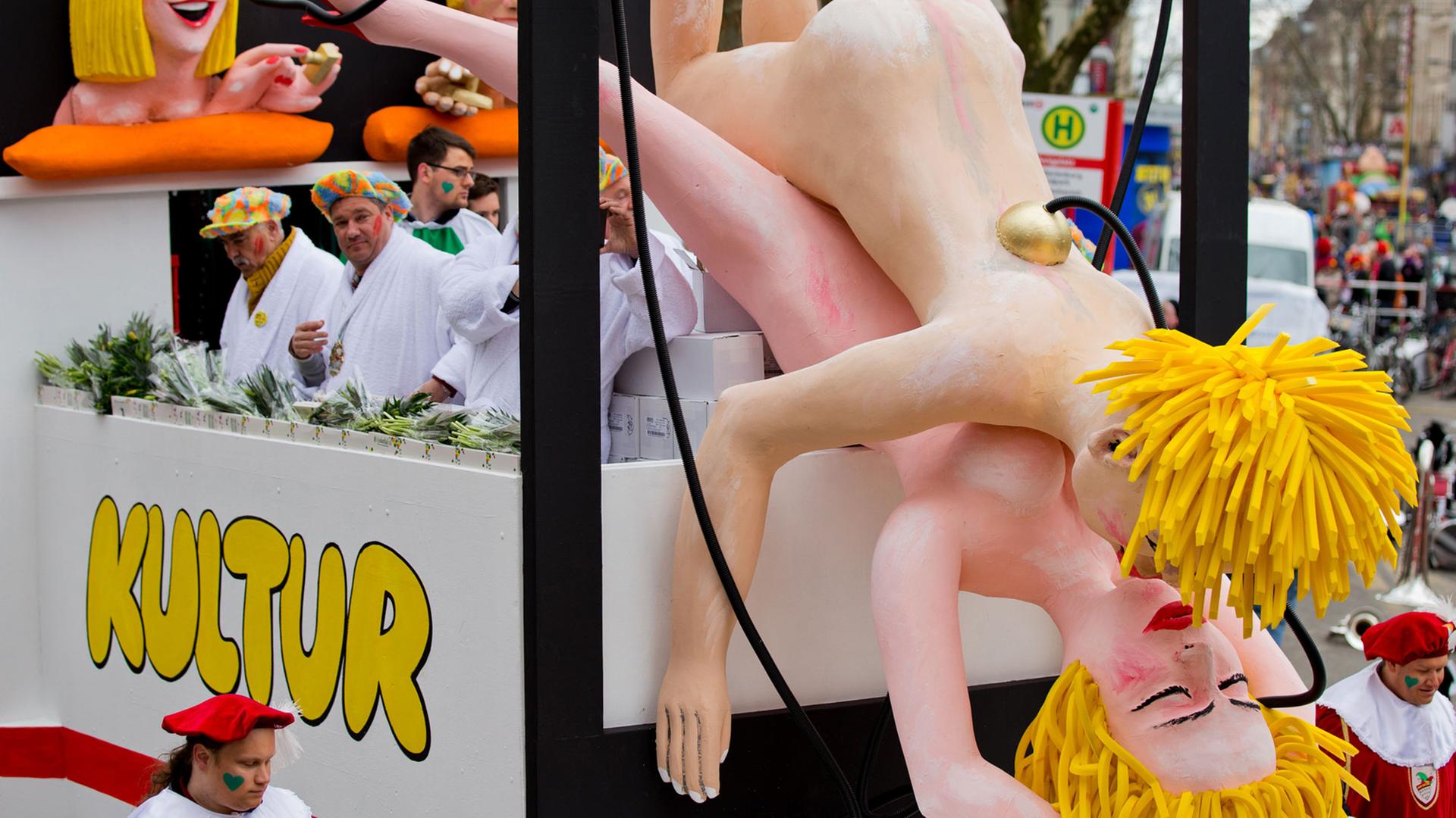 Ein Mottowagen zeigt beim Rosenmontagszug in Köln in Form künstlicher Figuren die Karikatur zweier Frauen beim Sex.