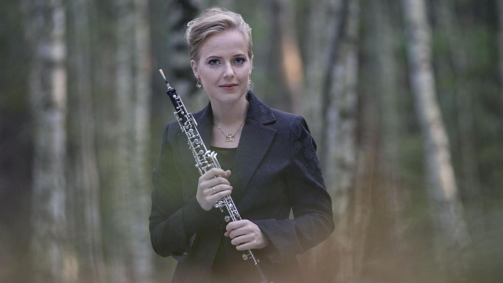 Die Oboistin steht mit ihrem Instrument in einer romantischen Waldlandschaft. Die Oboistin steht mit ihrem Instrument in einer romantischen Waldlandschaft.
