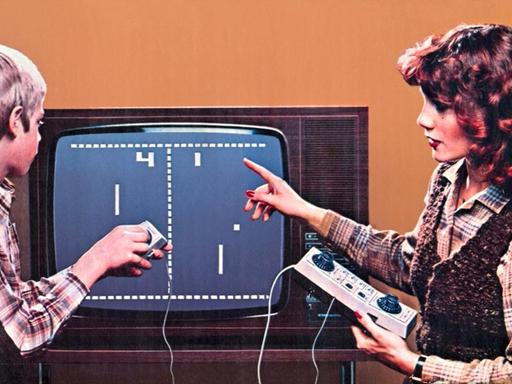 Eine Frau und ein Junge sitzen vor einem Monitor und spielen ein Spiel.