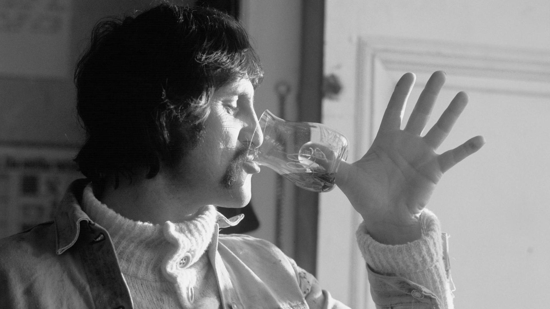 Der Designer Luigi Colani trinkt aus einem Weinglas, das statt eines Stiels eine Vertiefung für den Daumen im Boden hat.